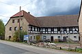 Wohnstallhaus (über Hakengrundriss), Seitengebäude und Scheune sowie Hofmauer mit Pforte und Torpfeilern eines Bauernhofes