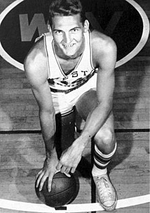 Jerry West, hukende og holder en ball i bakken.