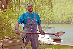 Laborer in bib overalls Digging the fire pit.