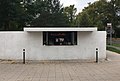 Kiosk z napojami w stylu Bauhaus w Dessau, ma jeden bok zaokrąglony, a drugi prosty, czerwony neon stanowi jedyną dekorację. Kiosk autorstwa Ludwiga Miesa van der Rohe (1932)