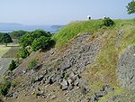 Monte com restos de fundações de pedra.  No fundo distante está a sé.