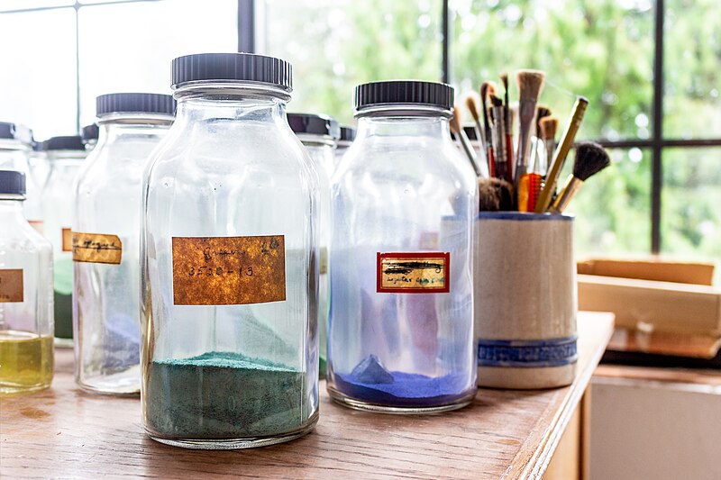 File:Old Glass Jars full of paint colors, in background there are Paint Brushes (27368479778).jpg