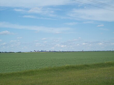 View of Regina from a distance on Saskatchewan Highway 1. The city is situated on a broad, flat, and largely waterless and treeless plain.