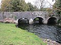 Riverstone Bridge, een brug van vier bogen (de vierde boog is aan de linkerzijde, afgesloten met jute)