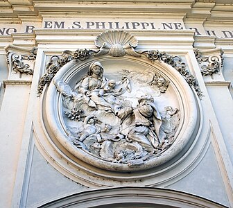 Fasadens högrelief Jungfrun och Barnet uppenbarar sig för den helige Filippo Neri.
