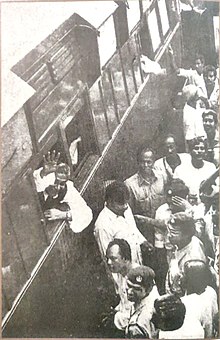 Sheikh Mujib waving to crowds from a train during his election campaign in 1970 Sheikh Mujibur Rahman 1970 election campaign train station.jpg