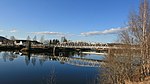 Foto einer Brücke über ein Gewässer mit einigen Häusern auf der anderen Seite