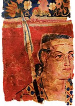 A 1st century image of a soldier in a red uniform, part of the Sampul tapestry, found in north-western China. The figure is believed to represent a member of the Yuezhi. UrumqiWarrior (cropped).jpg