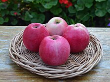 Panier contenant quatre pommes de couleur rouge et jaune.