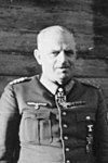 Black-and-white outdoor shot of an older man wearing a military uniform and an Iron Cross decoration suspended from his neck.