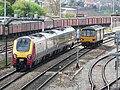 A Class 220 Virgin Voyager DEMU heads into Bristol Parkway station with a southbound cross-country as First Great Western Class 143 DMU 143617 departs the same station with a northbound stopping service to Cheltenham Spa.