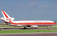 A Douglas DC-10-30 of Garuda Indonesia at Amsterdam Airport, showing their older livery, a red stripe, while the word "Garuda" is colored with red.