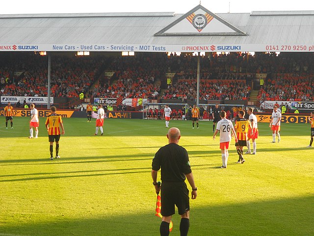 An assistant referee (front, in black) officiates a match between Partick Thistle and Dundee United