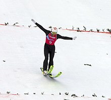 Прыгун с трамплина принимает прыжок.