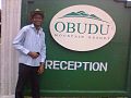 A man posing by the gate of Obudu Mountain Resort