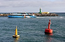 The entrance to the inner harbour of the Port of Fremantle, Australia, with a yellow special mark at left, a region A red port lateral mark at right, and a region A green starboard lighthouse in the background Quokka 1, Fremantle, 2020 (06).jpg