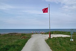 Bendera merah terbang di tepi tebing dengan Laut Utara di luar