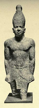 Statue of a pharaoh wearing a crown and a pleated kilt