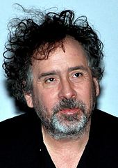 A smiling Tim Burton, dressed in black