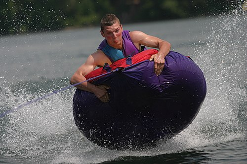 Towed tubing on a lake. Riders can often become airborne while passing over waves or wake from the motor boat or personal watercraft.