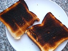 Two slices of overly-toasted white bread sit on a white plate.