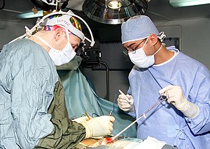 US Navy 030224-N-6920A-003 Electrician's Mate Fireman Alexander Pena, of Miami, Fla., receives on-the-job training (OJT) as he assists Lt. Jared Brooks, of San Diego, Calif., in a hernia repair operation.jpg