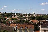 Vue d'un quartier d'une ville construit au flanc d'un coteau et alternant maisons individuelles et petits espaces verts.