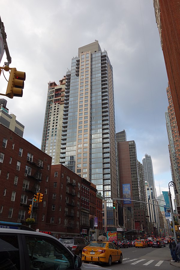 A lower-rise apartment building on the left side of the Avenue of the Americas in Manhattan, juxtaposed next to a skyscraper apartment building