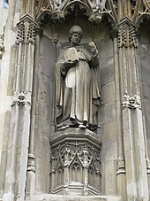 Foto van het standbeeld van een in verstek gezette bisschop met een afbeelding van Christus.