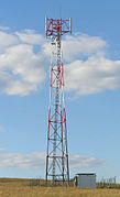 A BTS tower. The antenna is on top and the shelter housing the BTS on the right