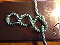 Step 2 of tying Cross constrictor knot: simple knot, sides pulled to form 3 loops