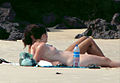 Two topless women sunbathing on a Tibau do Sul beach in 2007. The women are lying side-by-side, and shown from the side, so one of them is mostly hidden, except for her raised bare legs. The woman who is closer to the camera has her right breast, including nipple, clearly visible.