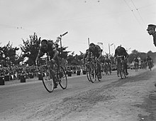 Fotografia em preto e branco mostrando vários ciclistas correndo.