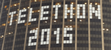 De petits caractères de texte en pixel art sur les fenêtres de la Tour Montparnasse lors d'un Téléthon