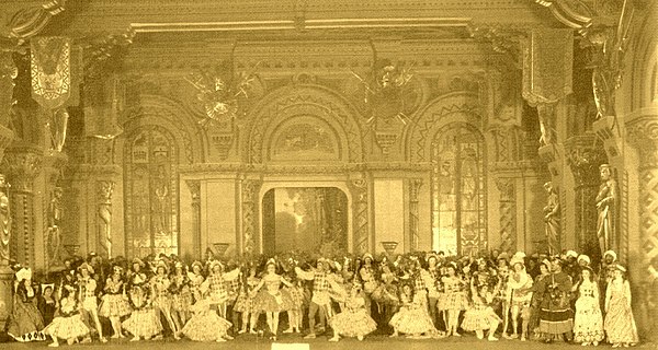 The stage of the Mariinsky Theatre with the cast of act I/scene 1 of the original production of Petipa's Raymonda. In the center is Pierina Legnani, c