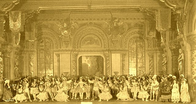 The stage of the Mariinsky Theatre with the cast of act I/scene 1 of the original production of Petipa's Raymonda. In the center is Pierina Legnani, c