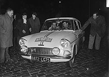 Fotografía en blanco y negro que muestra a dos hombres en un coche de carreras.