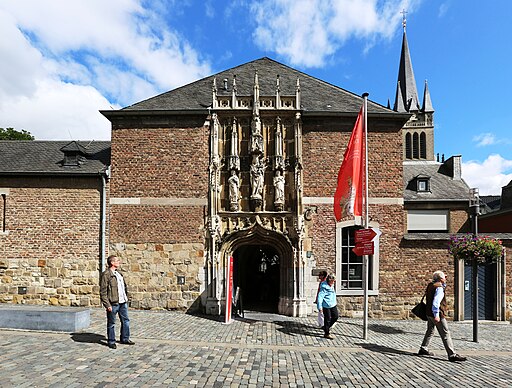 Aachener Domschatzkammer: Blick westwärts auf den Eingang; rechts im Hintergrund der Turm des Aachener Doms. Aachen, Johannes-Paul II.-Straße 15, gotischer Torbogen 15. Jahrhundert