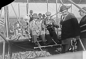 Photographie en noir et blanc de deux hommes dans un avion ancien ; carte postale ancienne.