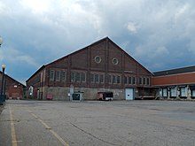 Bâtiment en brique avec une fondation surhaussée, beaucoup de fenêtres et deux oculus au pignon.