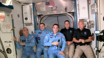 Anatoli Ivanishin, Ivan Vagner e Christopher Cassidy (à esquerda) dão as boas-vindas a Robert Behnken e Douglas Hurley na Estação Espacial Internacional.  Captura de tela da cobertura ao vivo da NASA da SpaceX Crew Dragon Demo 2 acoplada à Estação Espacial Internacional na manhã de domingo EDT, 31 de maio de 2020