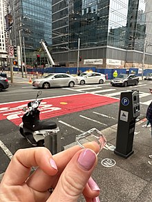 A pedestrian holds a glass fragment from the shattered window, found among others, nearly a block away from where the impact occurred in March 2023. Glass fragment from Millennium Tower falling window panes.jpg