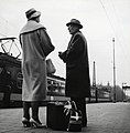 "HUA-168252-Afbeelding_van_twee_treinreizigers_op_het_perron_van_het_NS_station_Amsterdam_CS_te_Amsterdam_met_op_de_achtergrond_het_electrische_treinstel_nr_1208_.jpg" by User:Companje