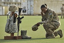 A U.S. Air Force Master Sargent kneels in front of a battlefield cross. MPOTY 2014 U.S. Air Force Master Sgt. kneels in front of a battlefield cross.jpg
