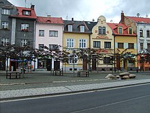 Straßenzug in der Altstadt mit einem aus einem Stapel Findlinge gestalteten künstlichen Brunnen