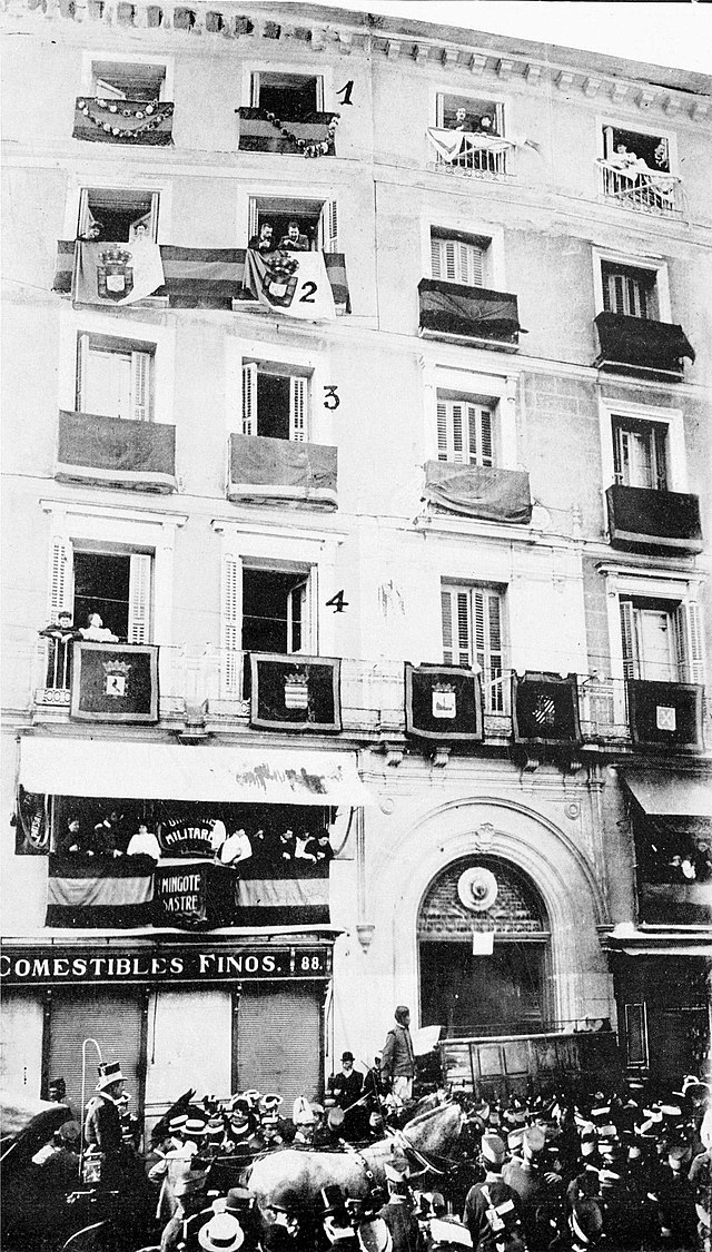 The facade of a five-story hotel, each window with its own balcony, and an active street scene below