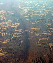 Oblique air photo of Sideling Hill, facing north, with the I-68 road cut near center, and the path of the National Road (Scenic US 40) visible to the south