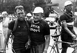 One men holding another men, on the right a man walking with a bicycle