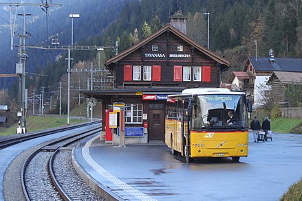 Un bus CarPostal devant une gare ferroviaire en Suisse.