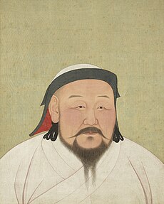 A head-shot style portrait of a middle aged man with flush cheeks and a black beard that extends from ear to ear, and is part in the middle, as well as a long mustache extending out horizontally rather than down. He is wearing a white robe and a black trimmed white had with a red inside lining.